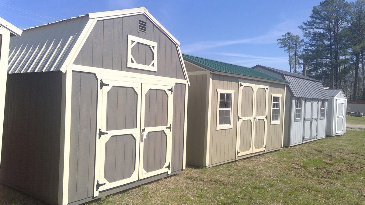 A row of sheds is lined up in a field.