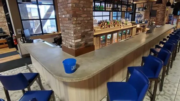 Empty café bar with blue chairs, brick columns, and a long countertop inside a modern restaurant.