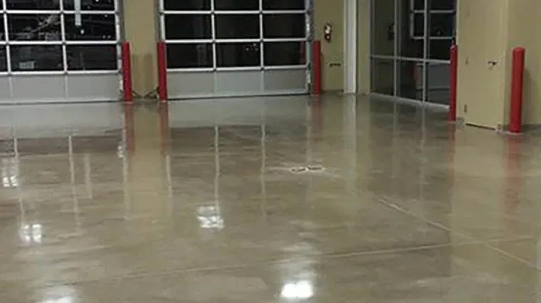 Empty indoor garage with polished concrete floor and red posts near large bay doors