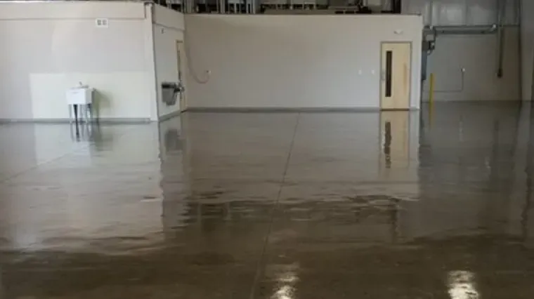 Empty warehouse interior with a polished concrete floor reflecting the walls and ceiling.