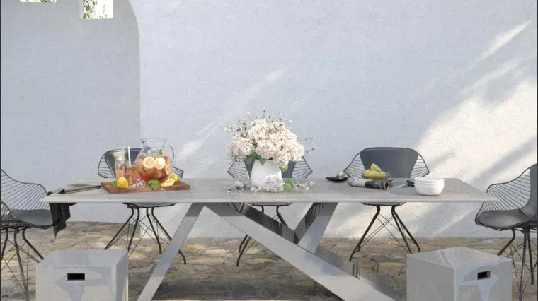 Outdoor table setup with fruit and flowers on a patio against a white wall