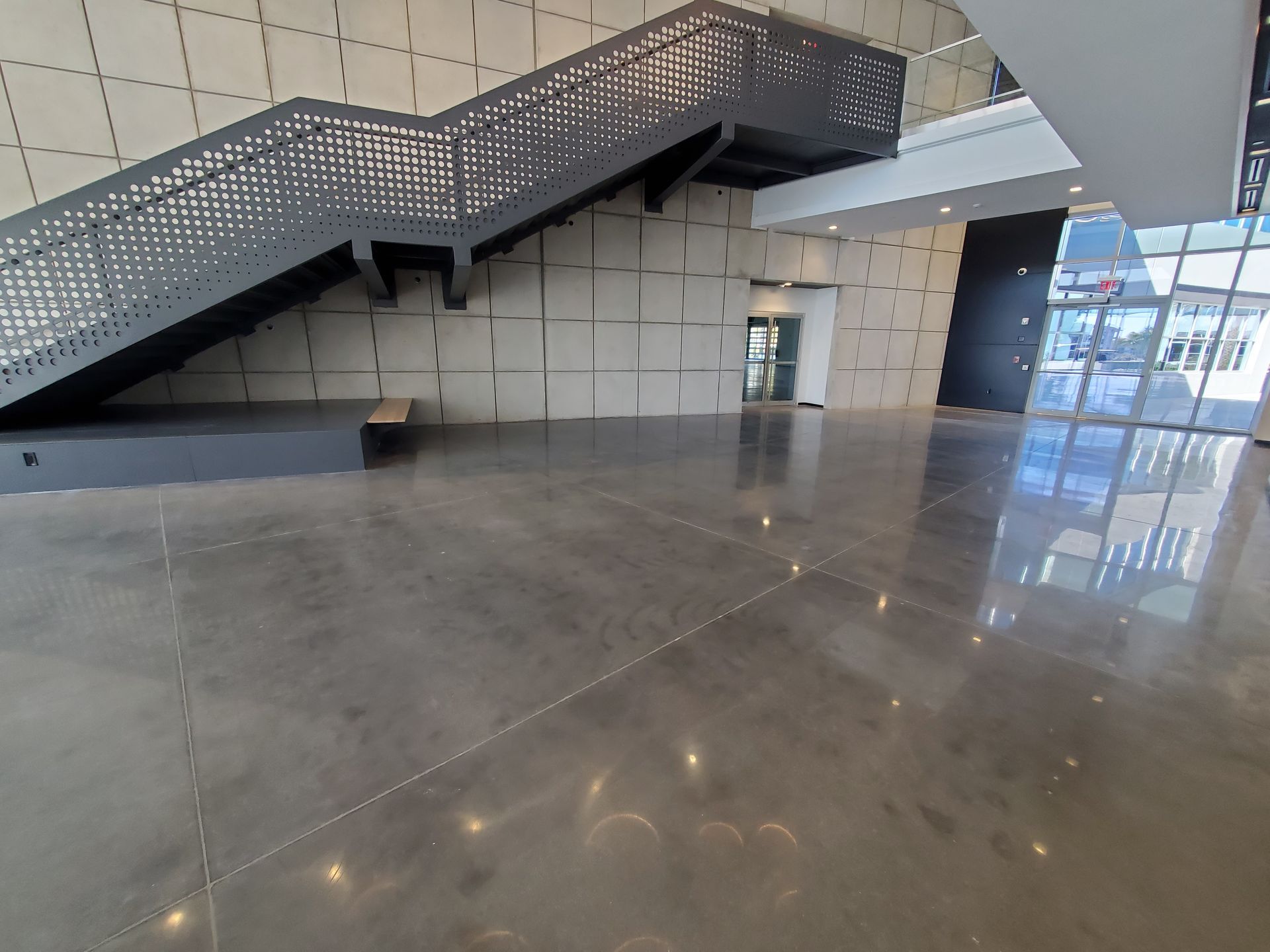 Empty polished lobby with wide staircase and glass railing reflections on the floor