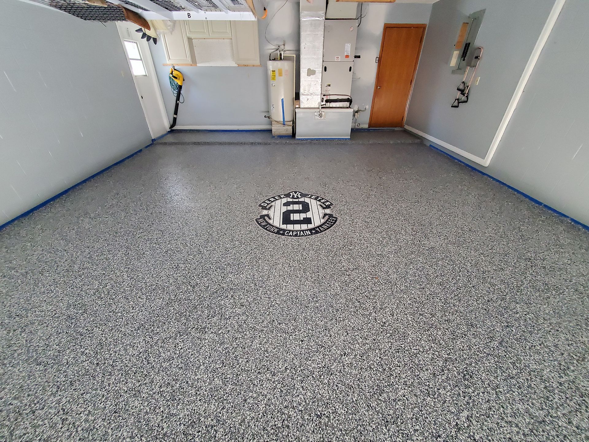 Empty gray room with speckled floor, wall-mounted utilities, and a floor drain in the center