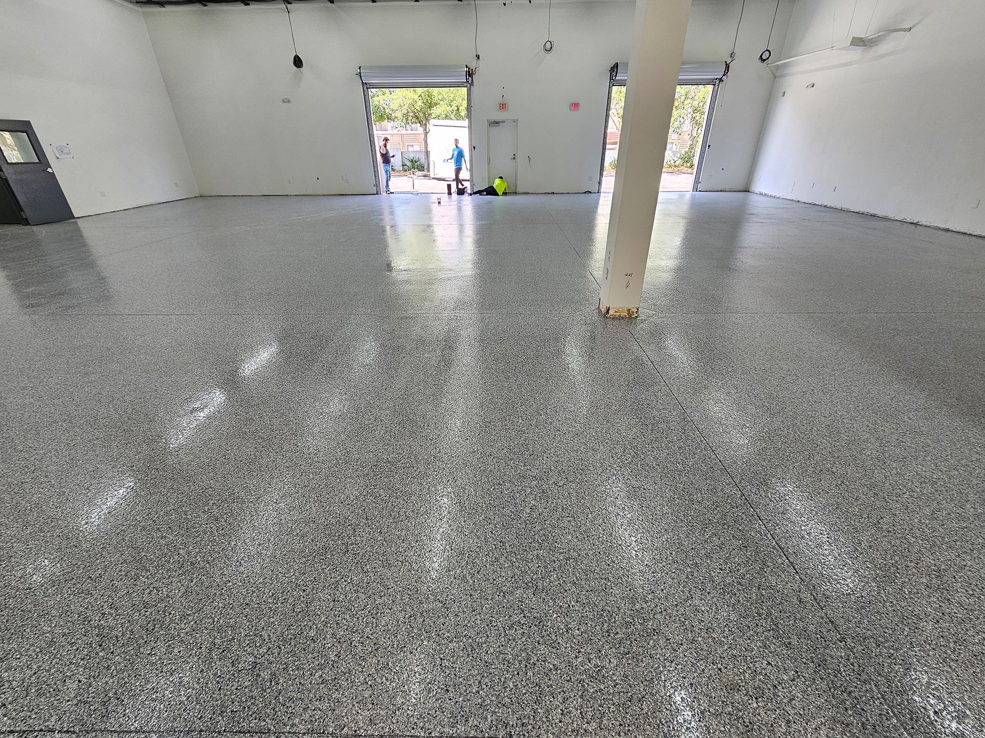 Empty white room with a glossy gray floor and open doorway in the distance