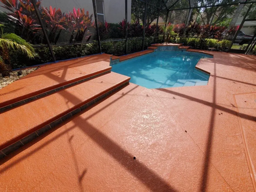 Orange patio with steps leading to a small blue backyard pool surrounded by tropical plants