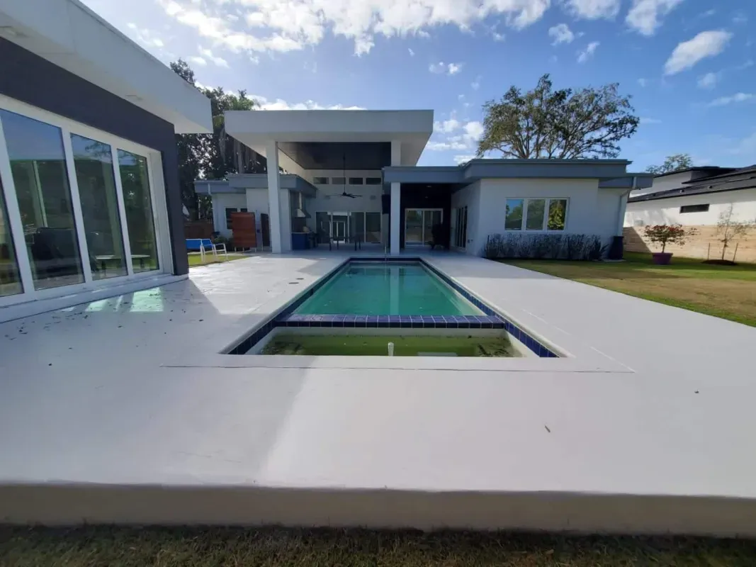 Modern home patio with a rectangular reflecting pool and landscaped lawn under a blue sky