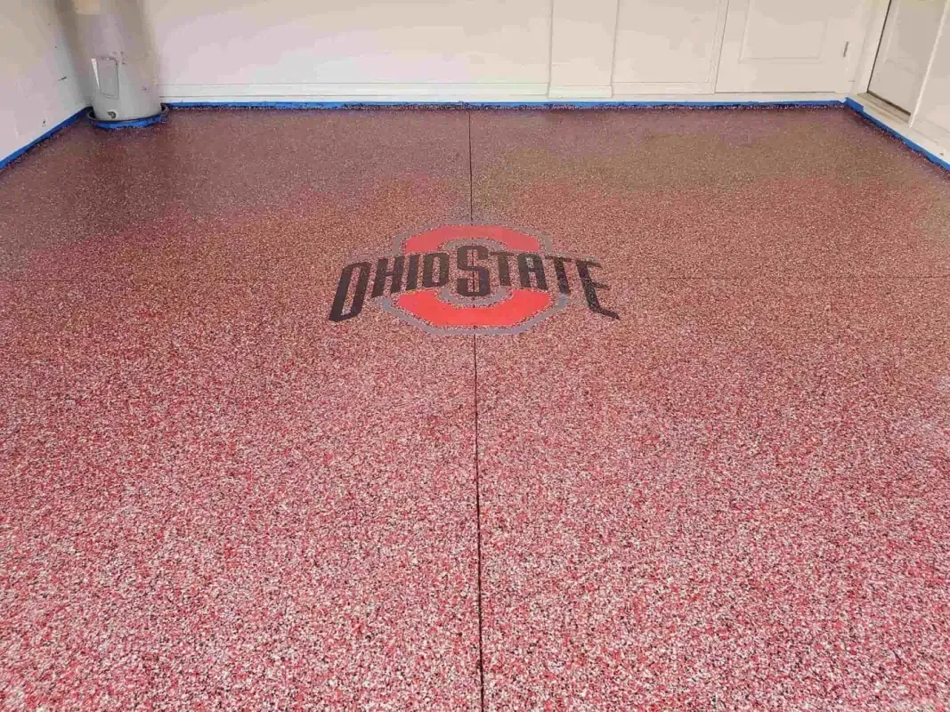 Empty room with red speckled epoxy floor and a black-and-red Ohio State logo centered on it