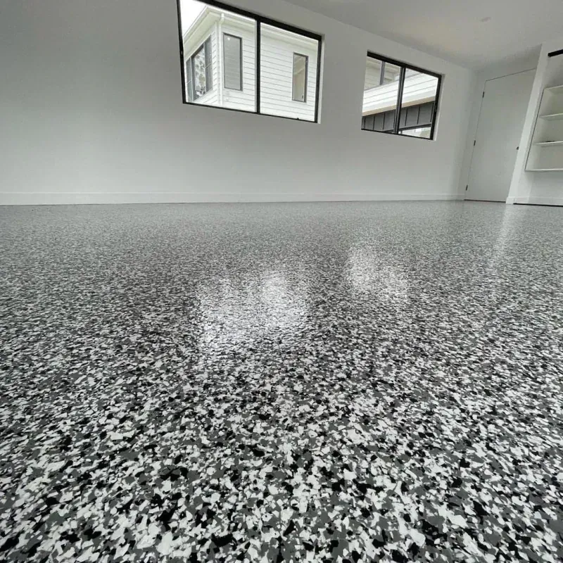Empty room with white walls and black-speckled epoxy floor, viewed from a low angle