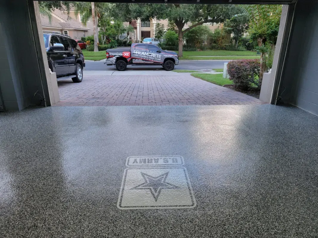 Garage floor with a star emblem, looking out to parked cars and a suburban driveway.