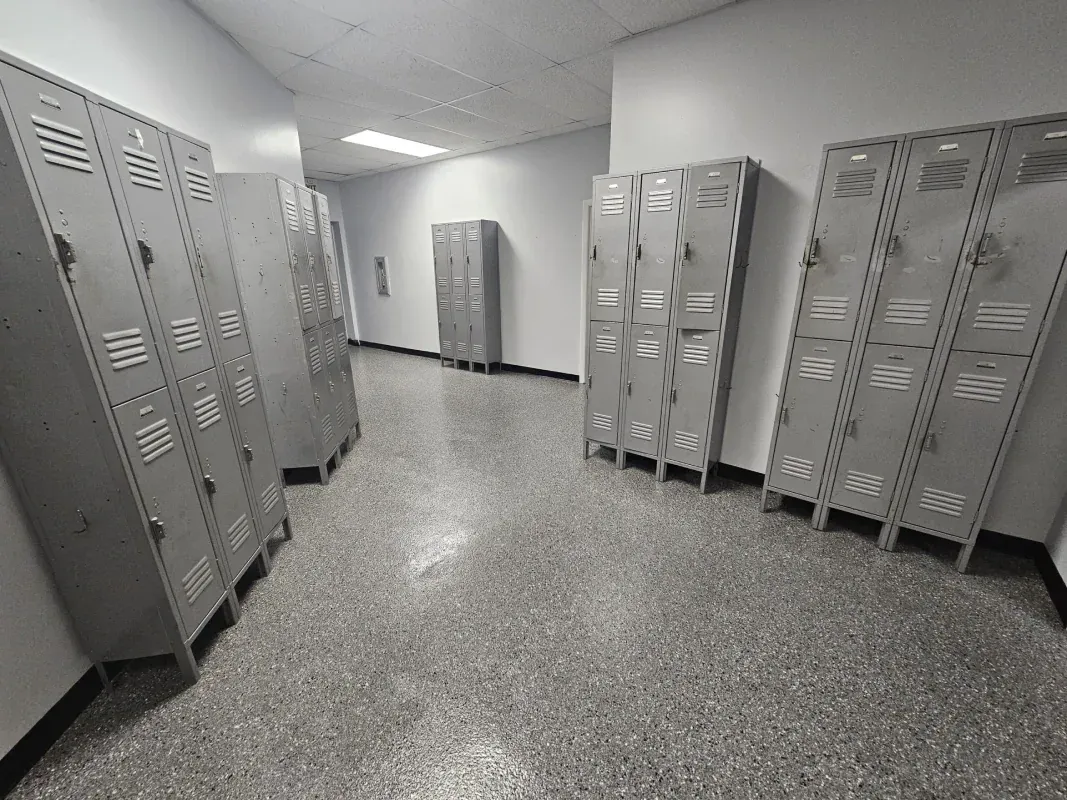 Locker room with rows of gray metal lockers and a speckled floor