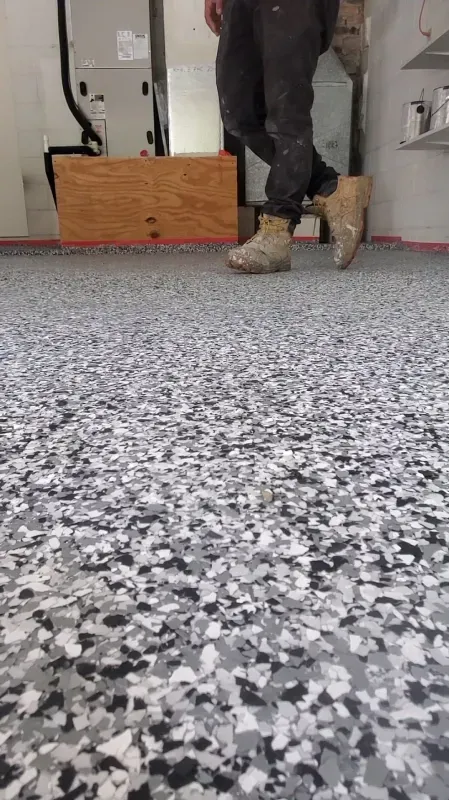 Person’s boots and lower legs standing on a speckled gray floor in a workshop or garage