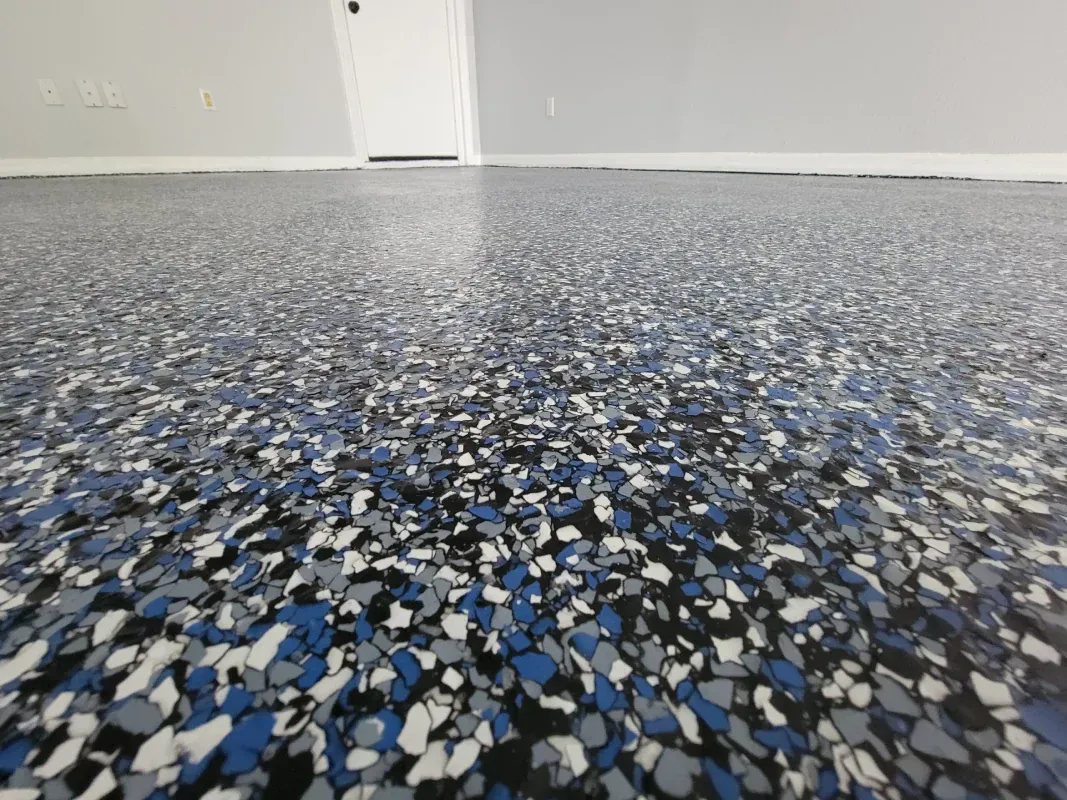Blue-and-gray speckled epoxy floor in an empty room with white walls and a closed door