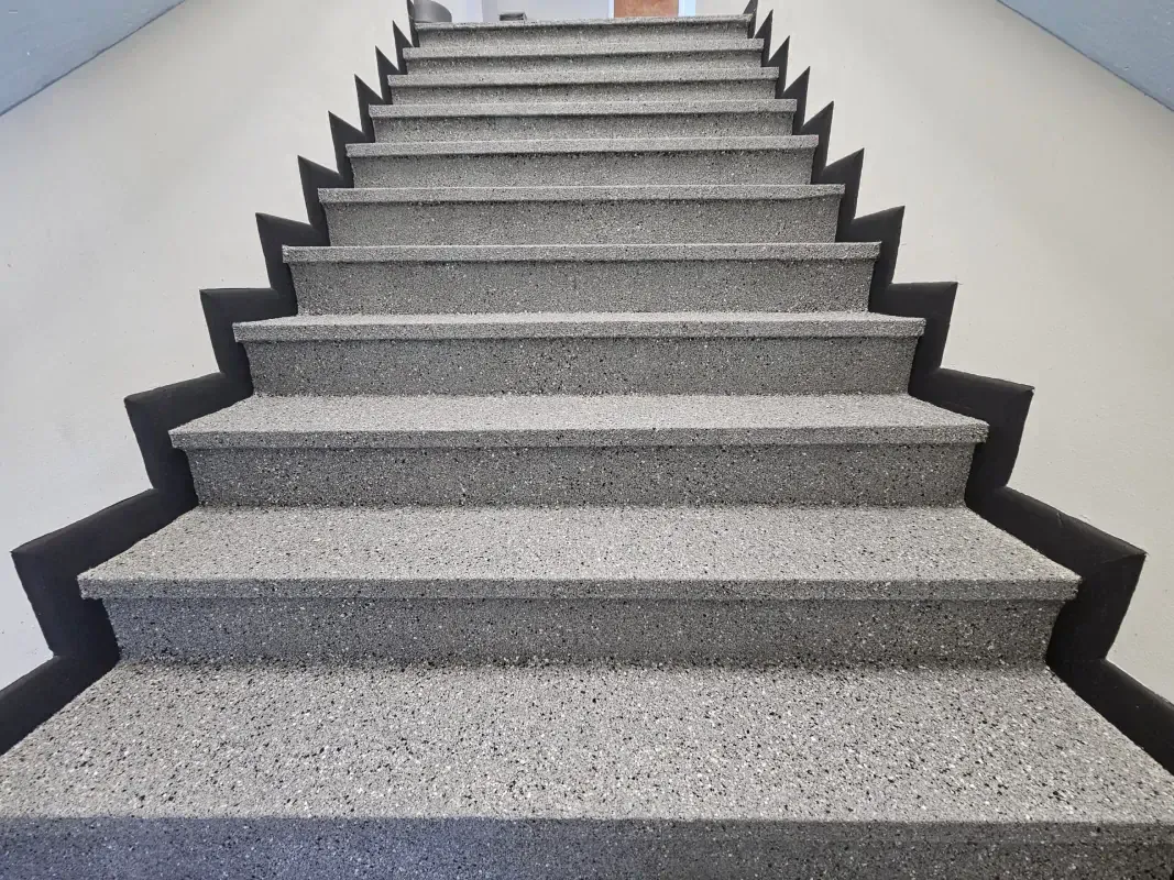 Gray carpeted staircase with black-edged steps ascending indoors