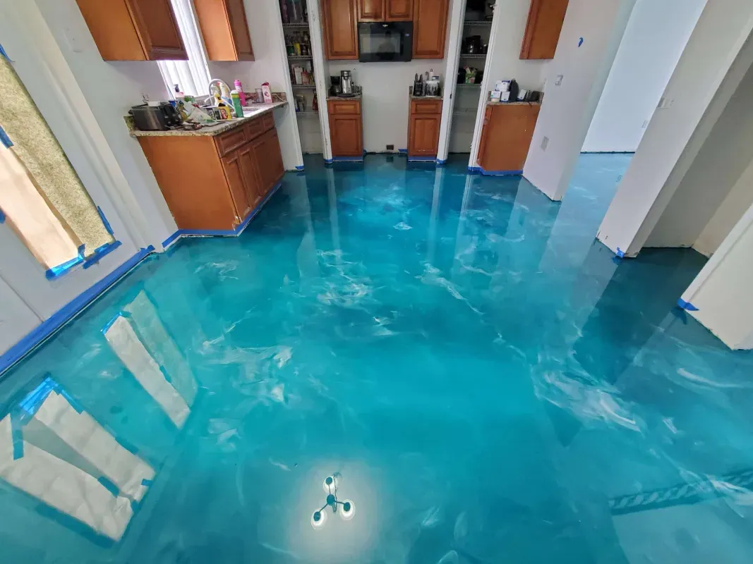 Bright blue flooded kitchen with cabinets and counters reflected on the water-covered floor