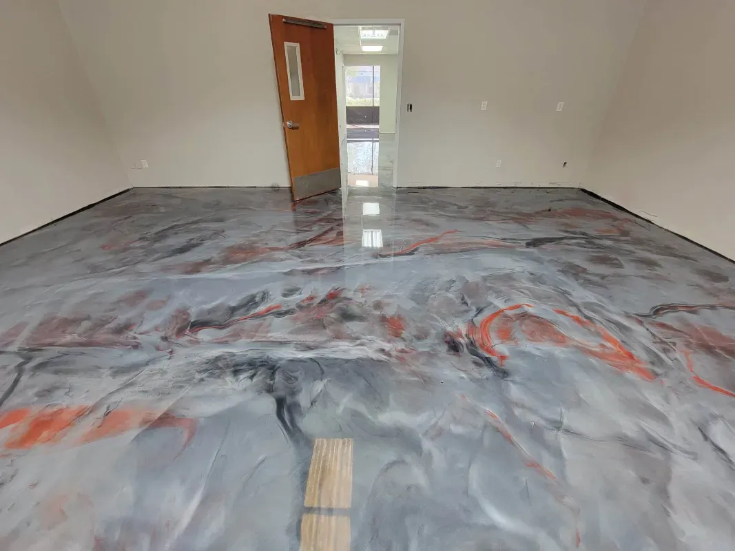 Empty room with glossy marbled gray and red epoxy floor and open doorway at the back