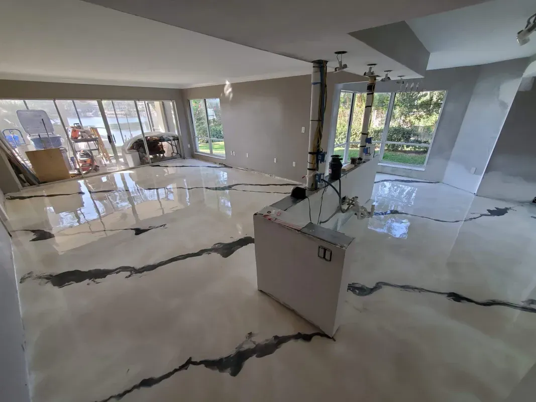 Empty modern living room with glossy white floors, black veining, and floor-to-ceiling windows overlooking greenery