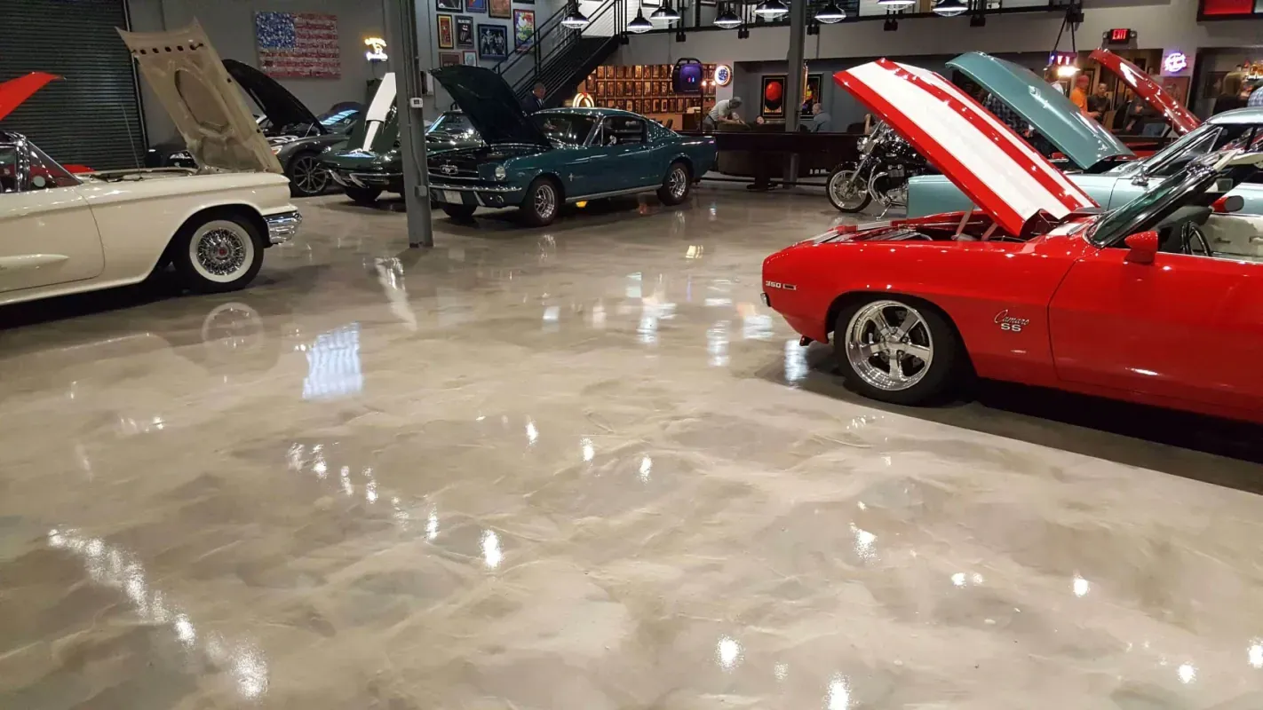 Classic cars displayed in a showroom, including a red convertible with its hood open and a cream coupe.