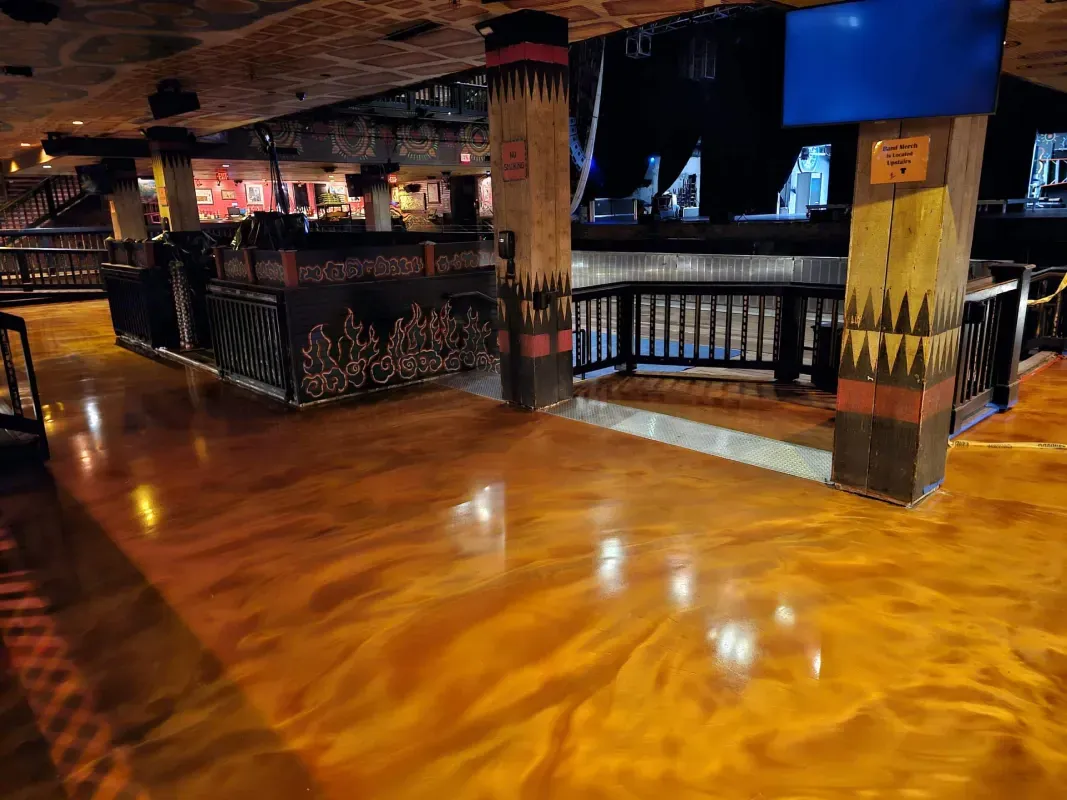 Empty indoor venue with polished wooden floor, railings, and dim colorful lights.