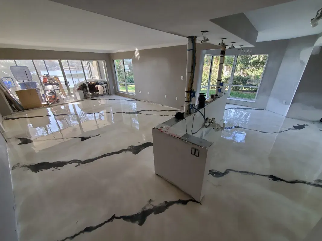 Modern open-plan living room with glossy white floors, marble veining, and large windows overlooking greenery