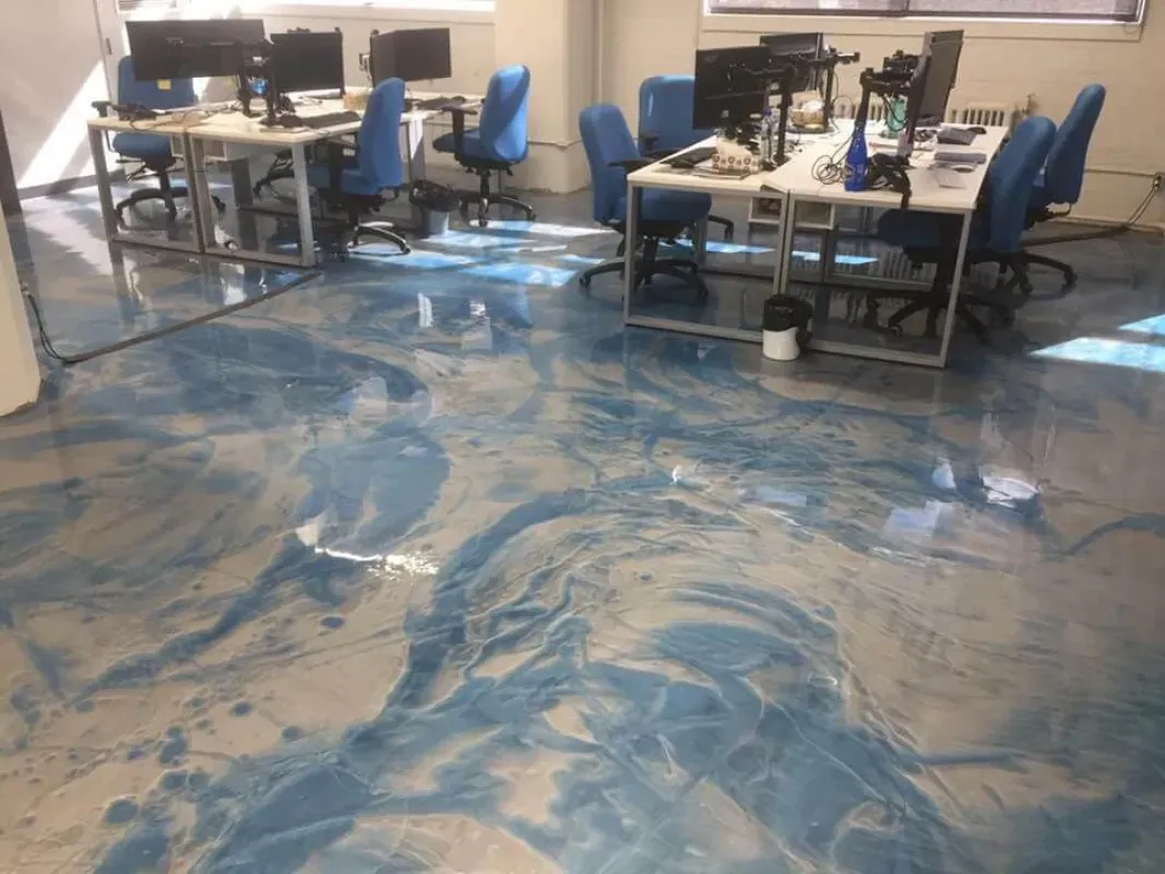 Office with desks and blue chairs reflected on a glossy blue and white patterned floor