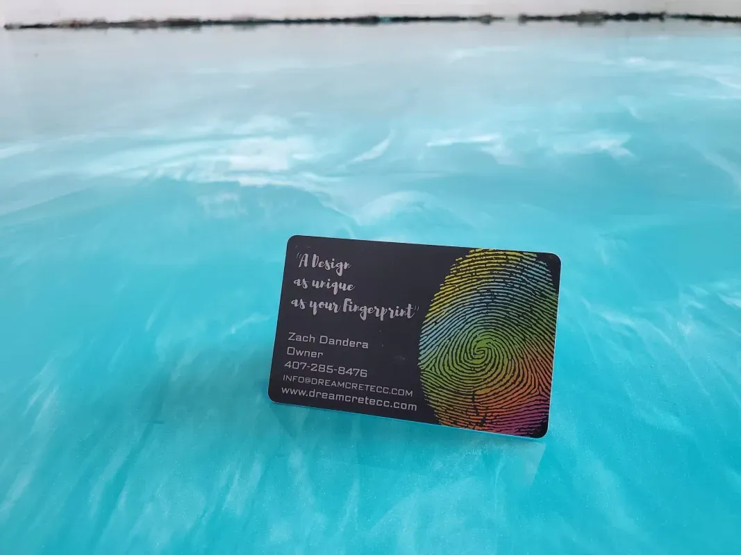 Small black card with colorful wavy pattern floating in bright blue water.
