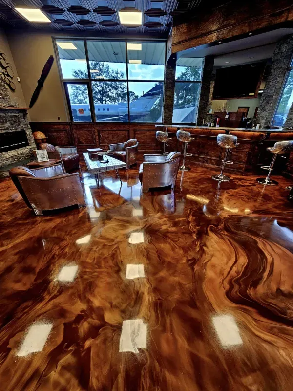 Glossy wood-grain bar interior with stools, chairs, and large windows overlooking snowy trees.