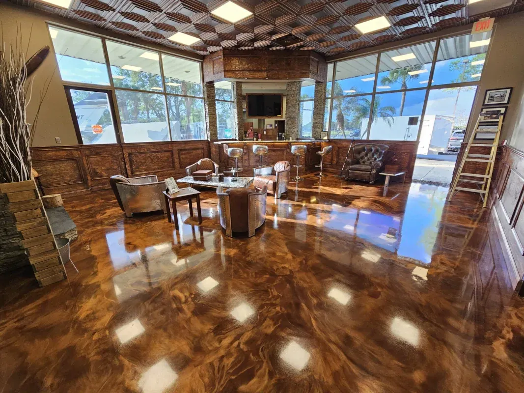 Empty modern room with shiny wooden floor, leather chairs, large windows, and a high patterned ceiling