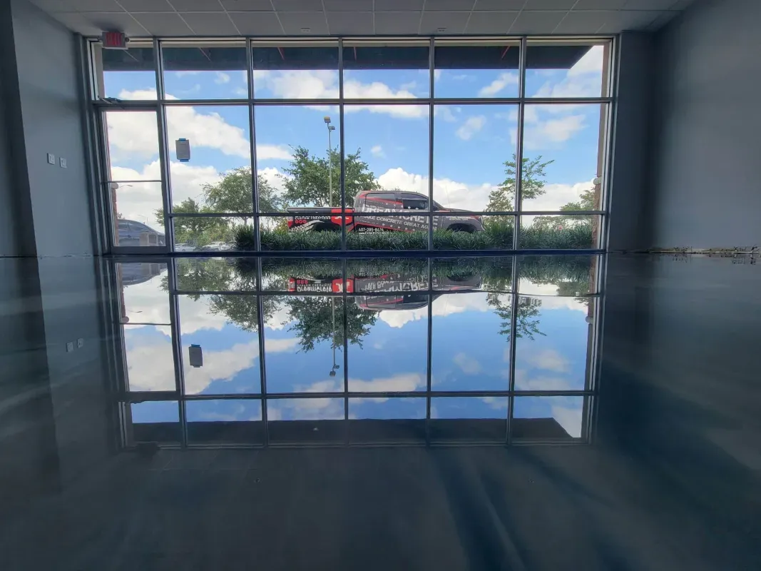 Indoor pool with a glass wall reflecting trees and blue sky outside