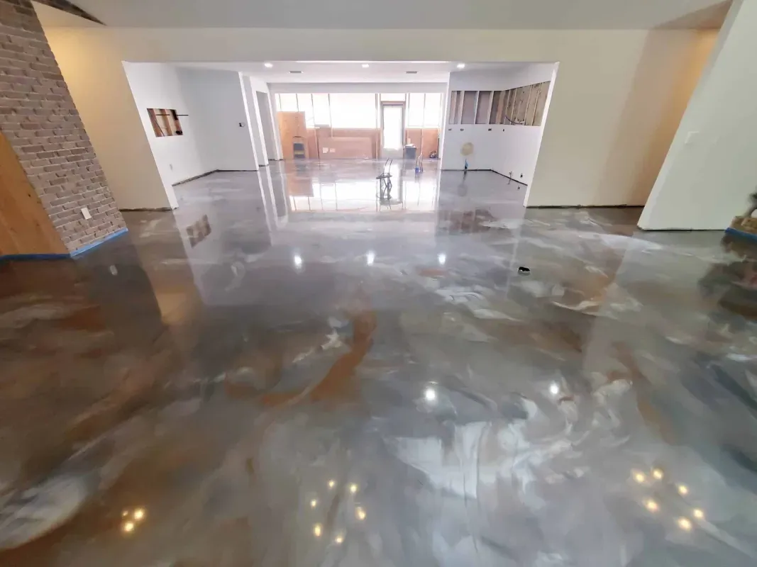 Empty modern lobby with polished reflective floor, white walls, and glass doors at the far end