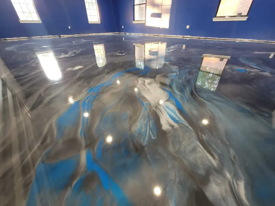 Polished concrete floor with blue and gray swirls reflecting overhead lights in an indoor room