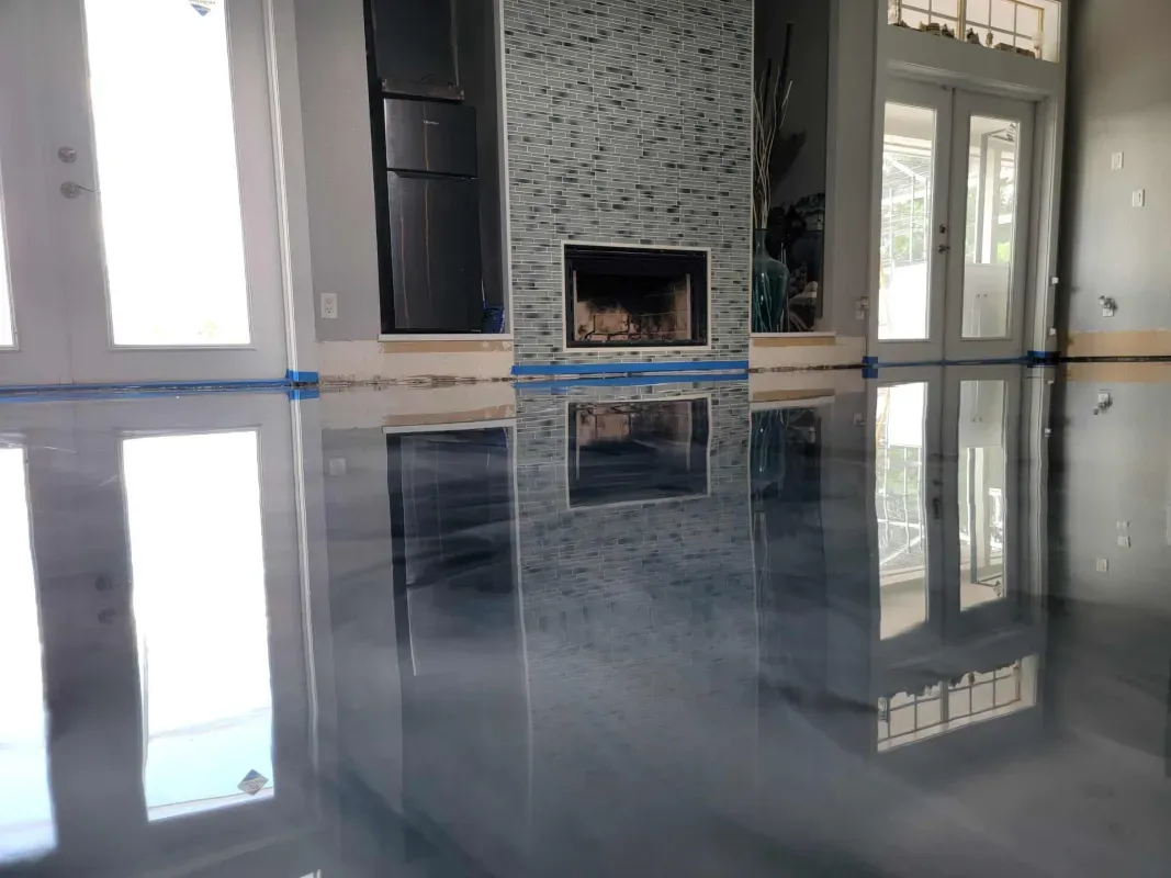 Empty room with glossy gray floor reflecting windows and a tiled fireplace wall