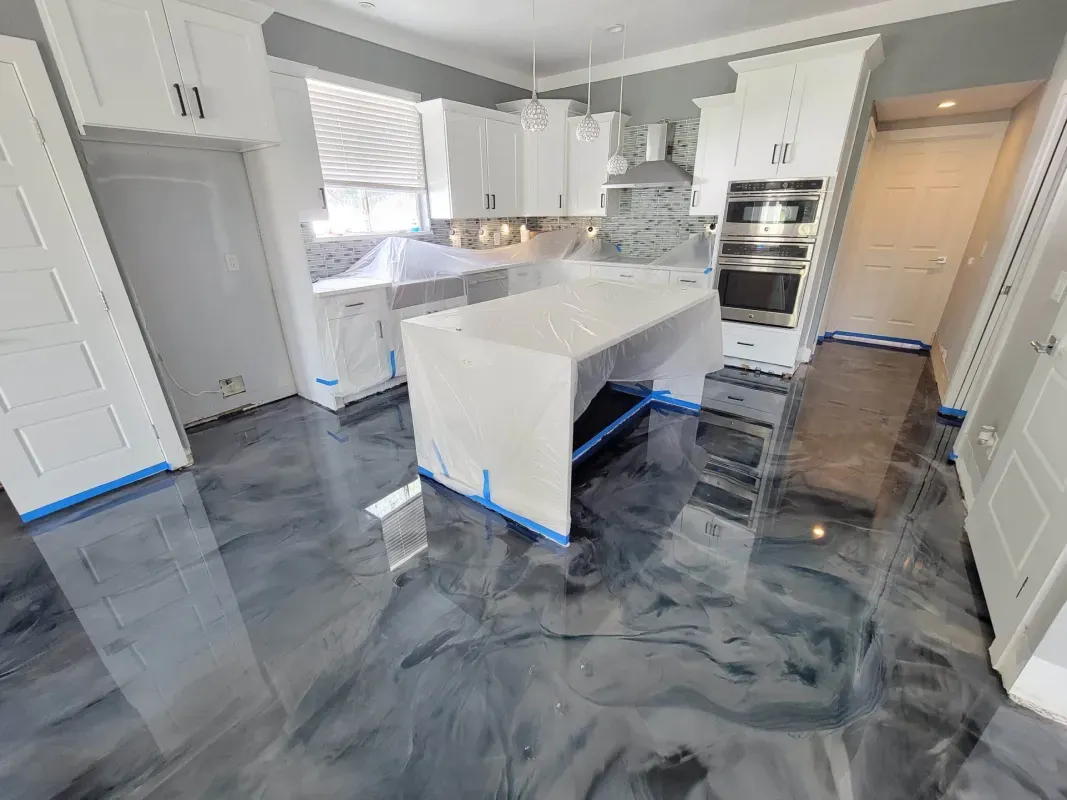 Modern kitchen with glossy gray floors, white island, and stainless steel appliances under bright natural light