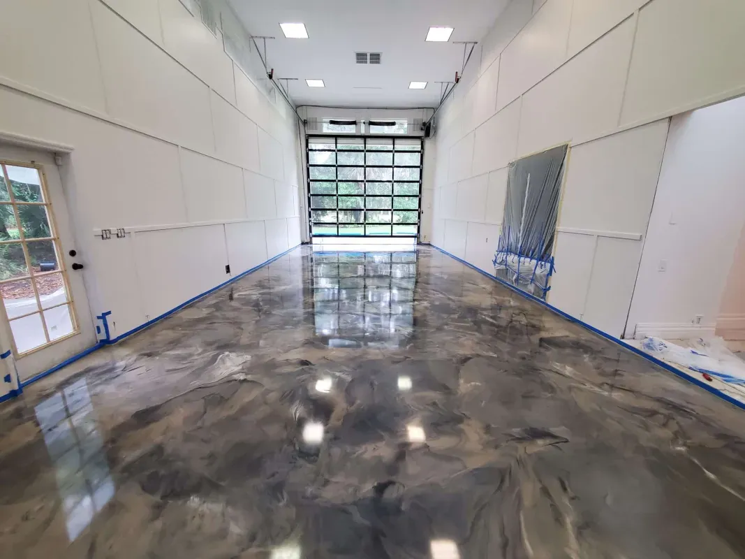 Empty industrial room with glossy concrete floor, white walls, and a large garage door at the far end