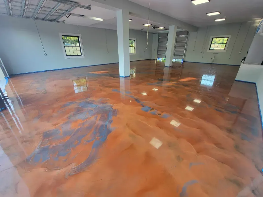 Empty room with glossy orange-and-gray epoxy floor, white walls, and windows.