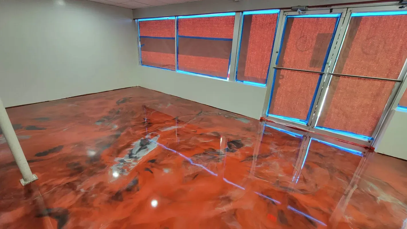 Empty room with glossy red floor and large windows covered by orange blinds