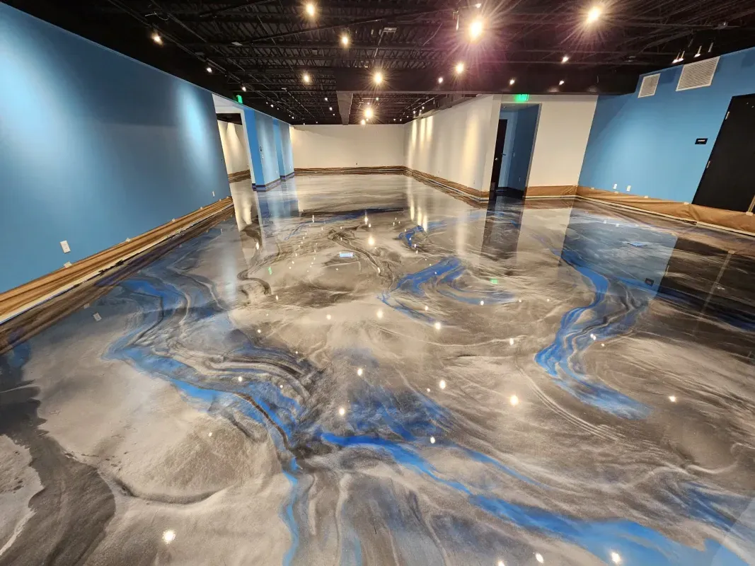 Empty modern gallery with blue walls and a glossy marbled floor reflecting ceiling lights.