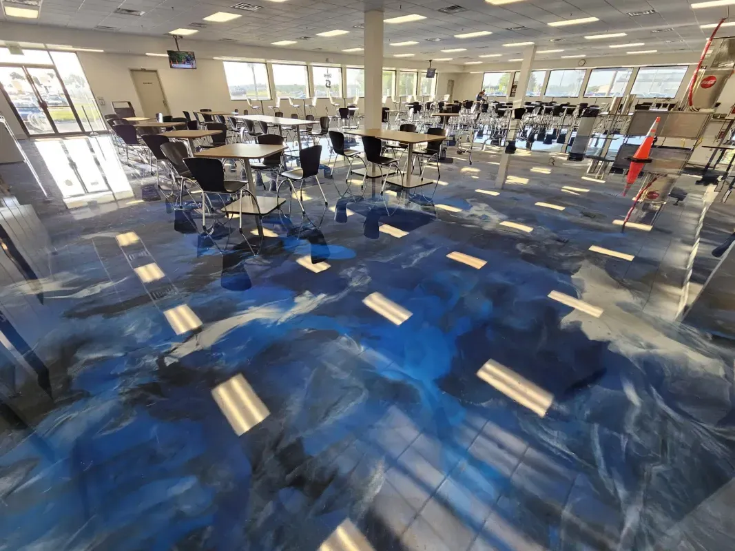 Empty modern office with blue patterned carpet and rows of desks under bright ceiling lights