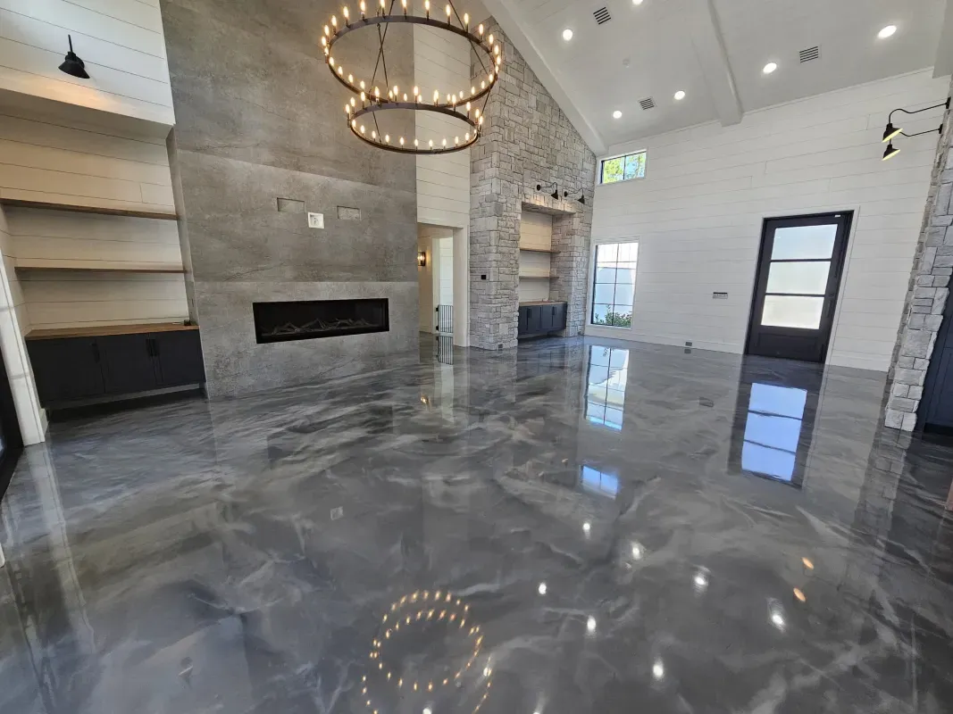 Modern empty living room with glossy gray floors, chandelier, fireplace, and white stone walls