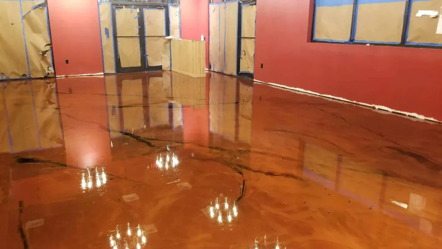 Empty room with glossy orange floor, red walls, and glass doors reflecting light