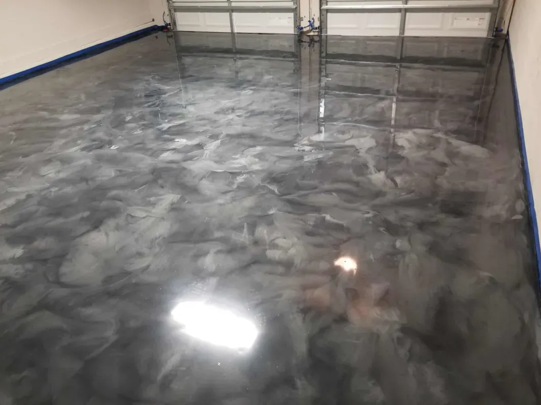 Glossy gray epoxy floor in an empty garage or room with white walls and blue trim