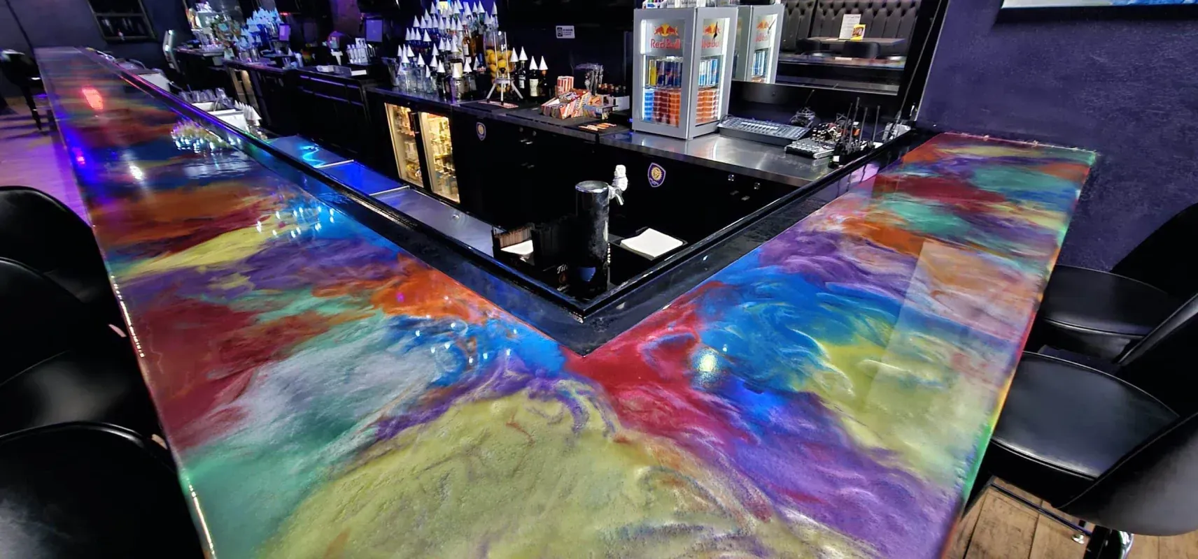Colorful abstract bar counter with rainbow paint and glowing lights in a dark lounge