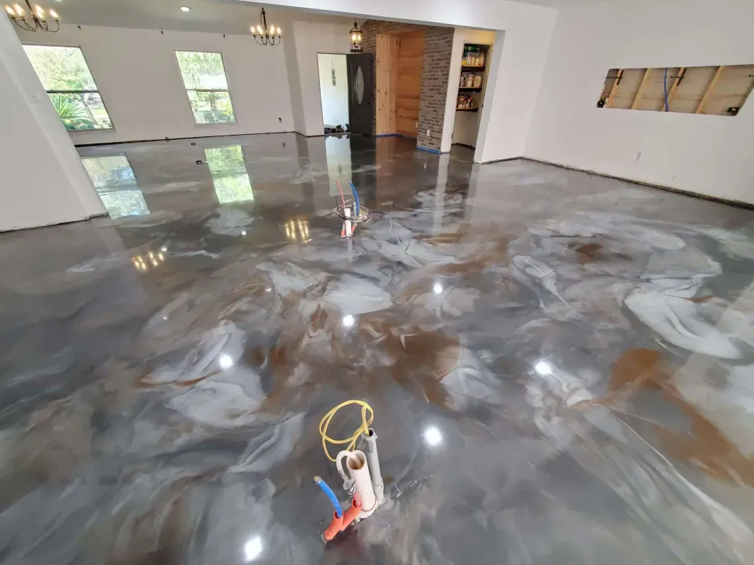 Vacant room with glossy gray epoxy floor and a small tool in the foreground, reflecting windows and ceiling lights