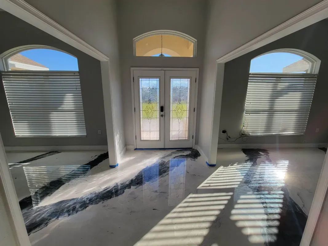 Bright empty living room with arched windows, double doors, and sunlight casting stripes on the floor
