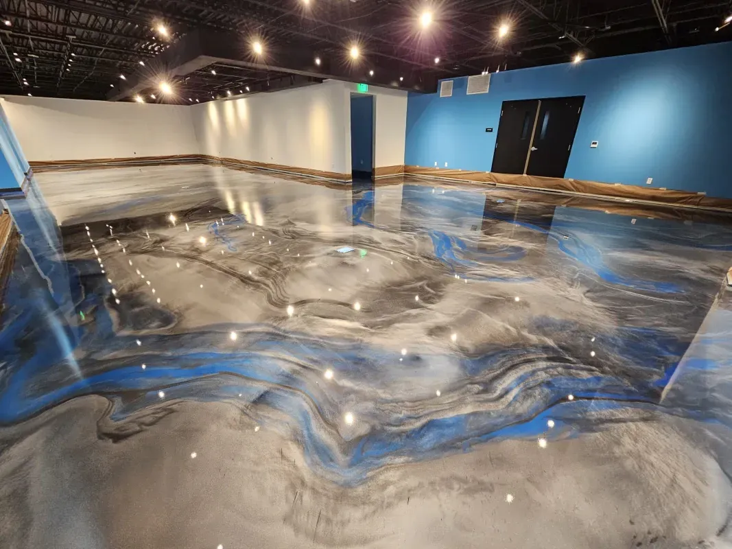 Abstract blue, gray, and white marbled floor in a gallery room with lights and white walls