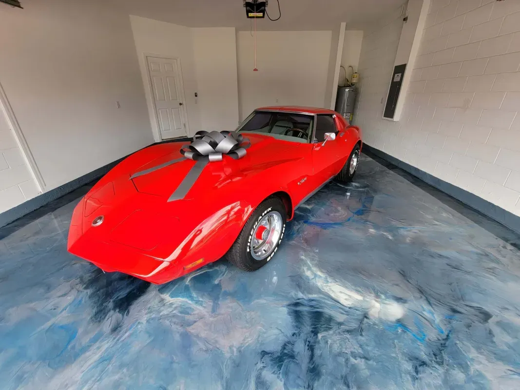 Red sports car with a blower in a garage with blue-stained concrete floor