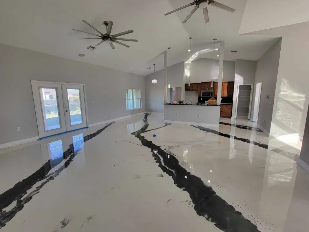 Modern open living room with glossy white floor, ceiling fans, and a kitchen area in back