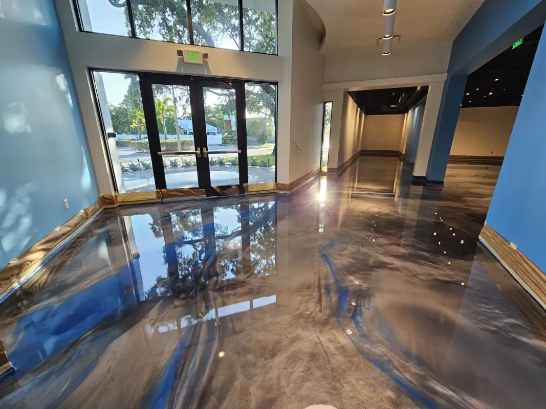 Glossy lobby with blue walls, glass doors, and polished floor reflecting light and windows