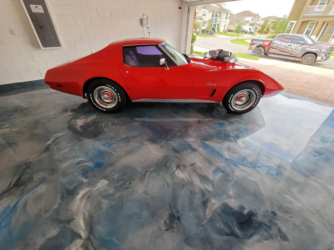 Red classic sports car parked in a garage with a glossy blue-gray marbled floor