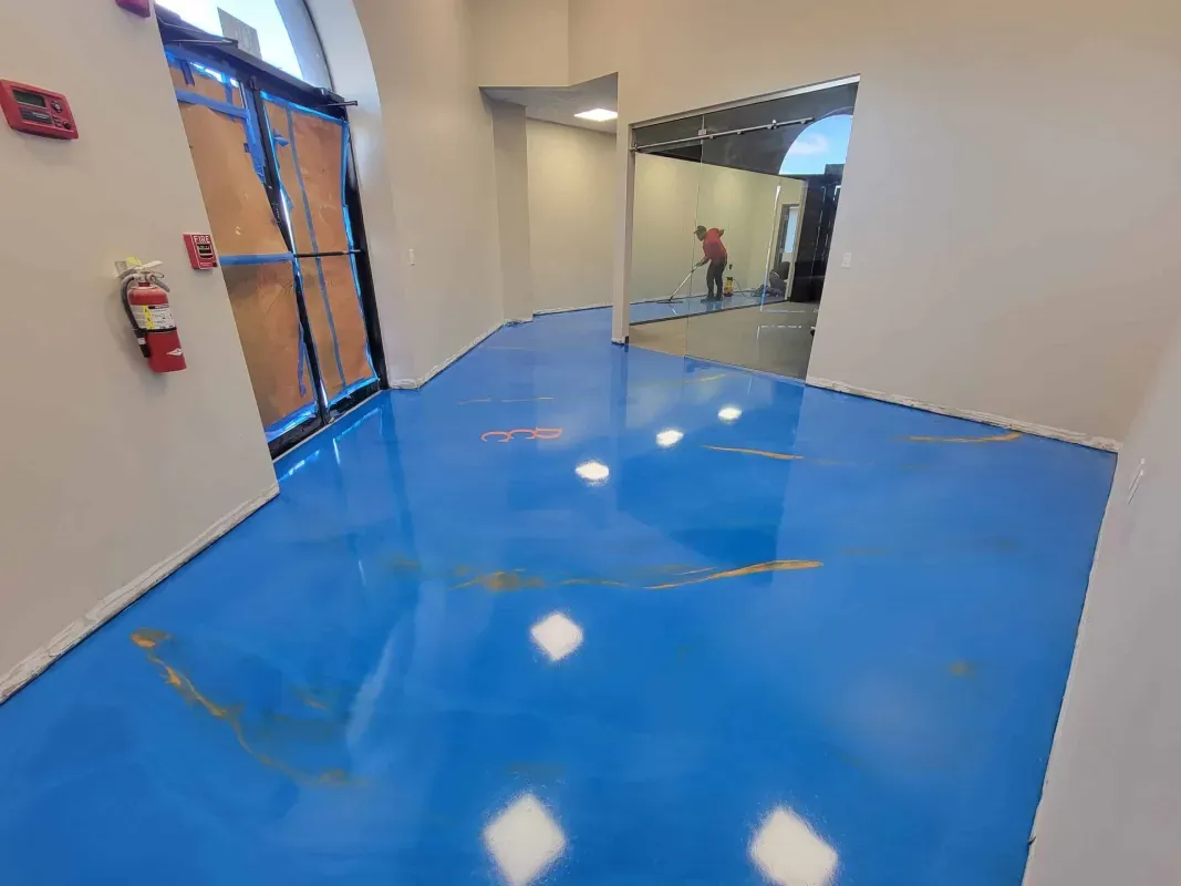 Bright blue polished hallway floor with white walls, glass doors, and reflections in a modern interior
