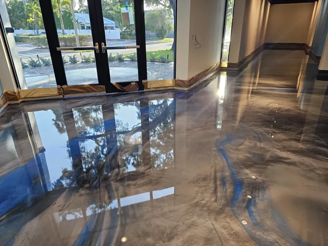 Polished marble lobby floor reflecting windows and hallway light in a modern building